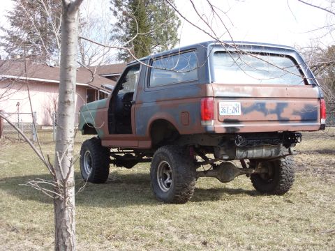 1988 Ford Bronco - This lifted 1988 Ford Bronco has a camouflage and rust paint scheme and is parked outdoors.