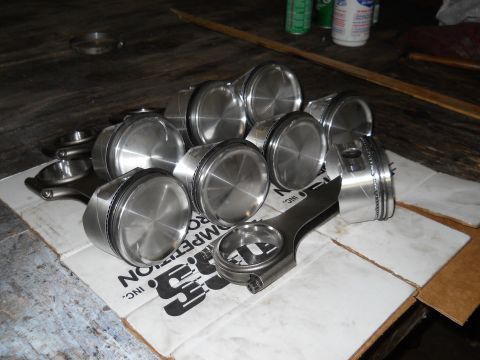2003 Ford Crown Victoria - Several pistons and connecting rods are laid out on a cardboard box.
