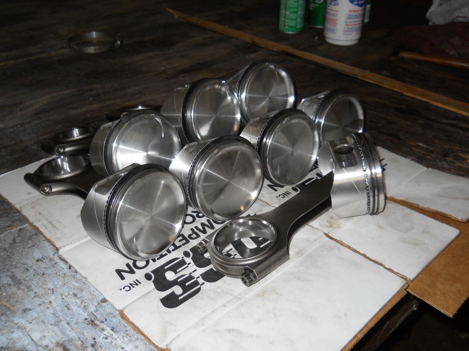 Pile of pistons and connecting rods on a cardboard box with 'COMPETITION' text