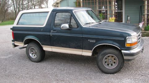 1992 Ford Bronco - This 1992 Ford Bronco is a dark green SUV with a tan stripe and a white removable top.