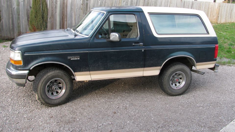 1992 Ford Bronco, dark blue with tan trim, parked on gravel