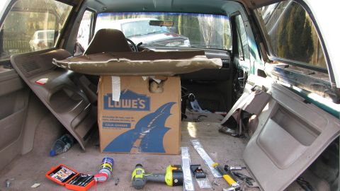1992 Ford Bronco - Tools and a Lowe's box are in the back of a vehicle with interior panels removed.