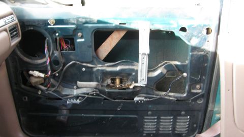 1992 Ford Bronco - The interior door panel is removed, revealing the window regulator and wiring harness of a 1992 Ford Bronco.