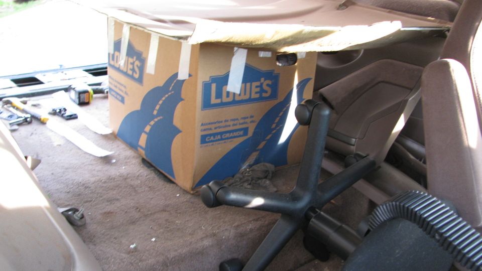 Interior shot of a vehicle's cargo area with a Lowe's box and an office chair