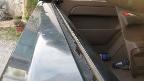 1992 Ford Bronco - Close-up view of the interior door frame and dashboard, showing wear on the rubber seal. A beverage can and bottle are on the floor.