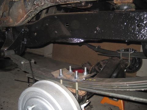 1979 Ford Bronco - Leaf spring and brake drum assembly shown from underneath a vehicle.