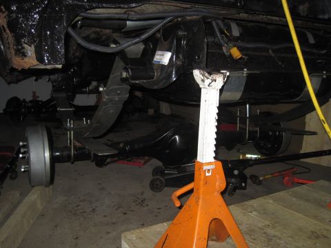 1979 Ford Bronco - The rear suspension and axle assembly of a vehicle are visible while it is supported by jack stands.