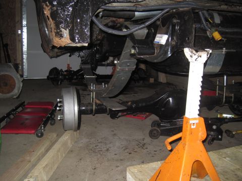 1979 Ford Bronco - Close-up of vehicle suspension components, including the rear axle and leaf springs, supported by jack stands.