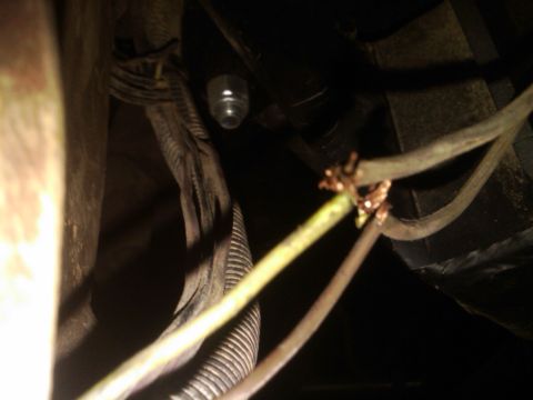 1982 Ford Bronco - A close-up view of a vehicle's wiring harness shows exposed copper connections and a clear bulb socket.