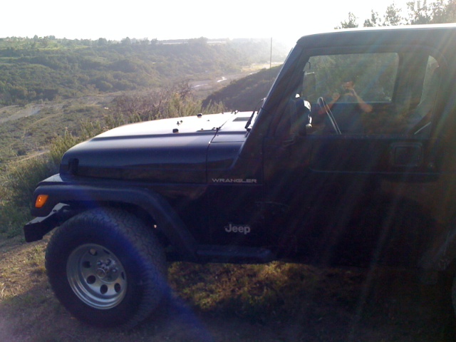 Dark blue Jeep Wrangler side view parked on a hill
