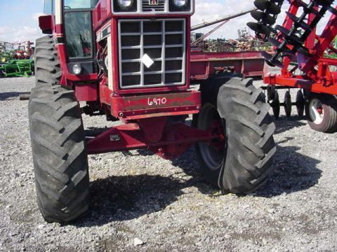 1992 Ford Bronco - A red tractor is parked next to agricultural equipment, with other farm machinery visible in the distance.
