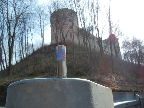 1999 Lincoln Town Car - A close-up of a pole with a voting sticker, with a castle and trees in the background.