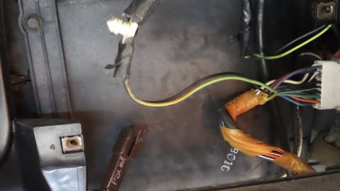 1994 Ford Bronco - Wiring repair inside a door shell or panel cavity: a bundle of black, yellow and green wires is spliced and wrapped in orange tape, feeding…