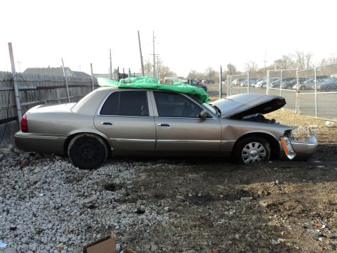 2004 Mercury Grand Marquis - A tan sedan sits in a gravel lot with its hood open and a green tarp covering the roof.