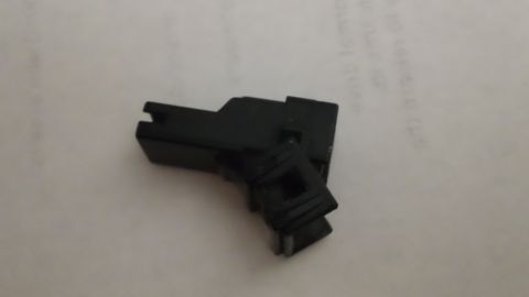 1994 Ford Bronco - A small black plastic wiring connector housing with a locking tab and open terminal cavity, photographed sitting on a sheet of white handwr…