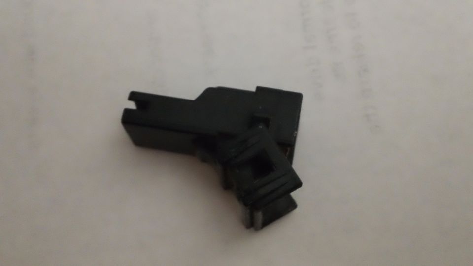 Small black plastic wiring connector housing resting on handwritten white paper