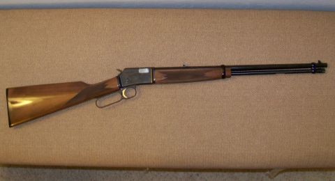 1994 Ford F-150 - A lever-action rifle with a polished wooden stock and a blued metal barrel and receiver is displayed against a textured background.
