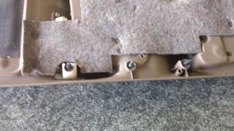 1994 Ford Bronco - Close-up of the back side of a tan door sill/rocker trim panel showing white plastic christmas-tree retainer clips screwed into place along…