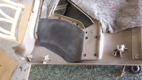 1994 Ford Bronco - Underside of a removed tan plastic rocker/kick panel trim piece with white push-in retainer clips still installed and a black felt sound-de…