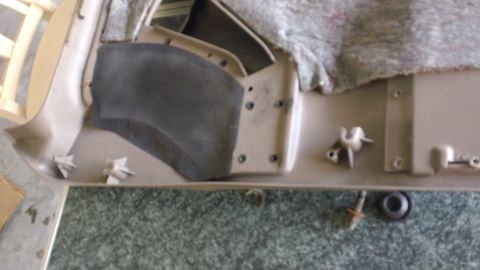 1994 Ford Bronco - Close-up of a vehicle's interior door panel trim, showing insulation and mounting hardware.