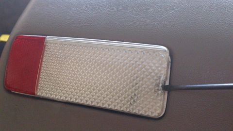 1994 Ford Bronco - A door courtesy light installed in a tan grained door panel, with a clear diamond-textured lens and a red reflector segment at one end. A b…