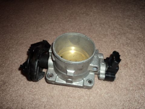 2004 Mercury Grand Marquis - A throttle body assembly, likely for an older vehicle, is shown on a carpeted surface.