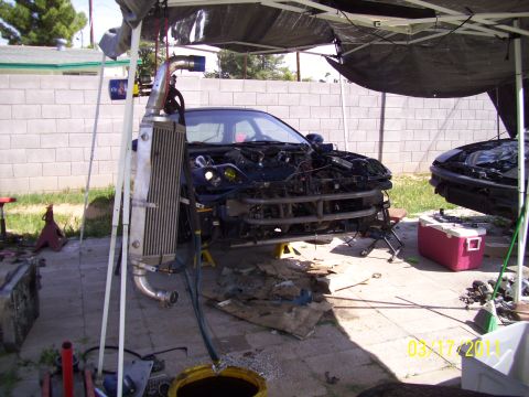 1995 Ford Probe - A car is being worked on outdoors, with its front end disassembled and an intercooler prominently displayed.