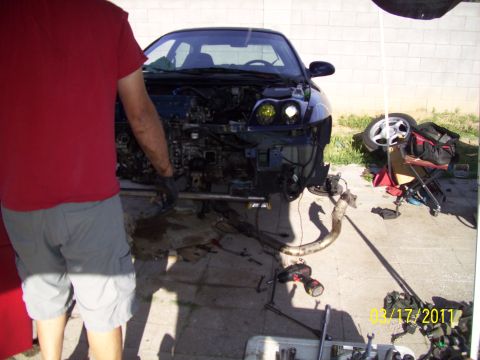 1995 Ford Probe - A person works on a car with its engine and front bumper removed, tools scattered around.