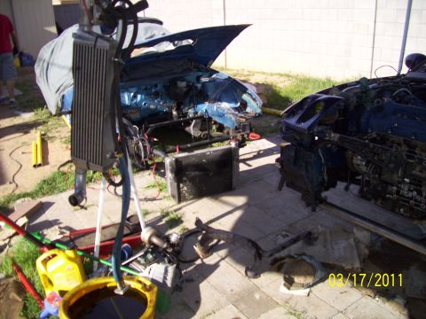 1995 Ford Probe - Two heavily disassembled blue cars are in a yard with various parts and tools scattered around them.