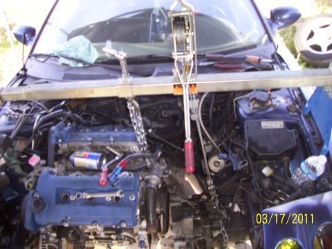 1995 Ford Probe - The engine is suspended by a hoist, indicating a removal or installation process is underway.