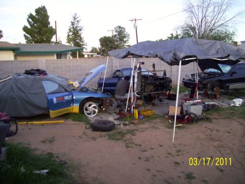 1995 Ford Probe - Multiple vehicles undergoing repair and disassembly in a yard on a sunny day.