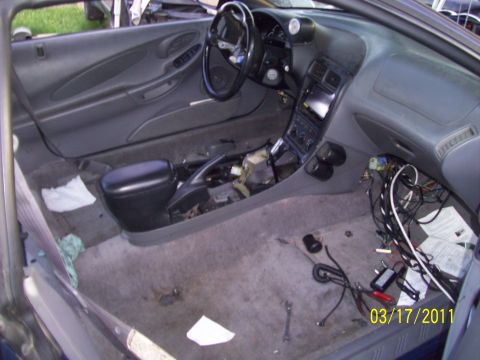 1995 Ford Probe - The interior of a car shows extensive disassembly, with wiring and components exposed on the floor and dashboard.