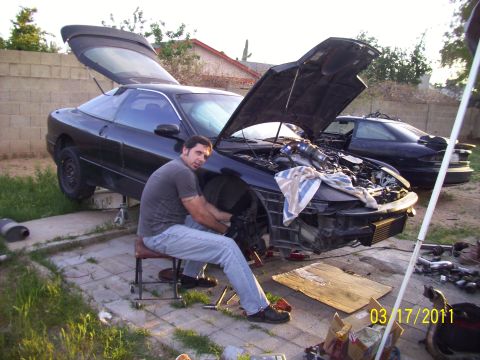 1995 Ford Probe - Man performs maintenance on a 1995 Ford Probe with its hood and trunk open; another Probe is visible in the background.