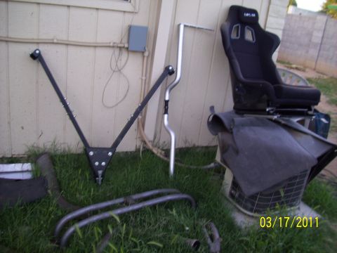 1995 Ford Probe - Various car parts, including a racing seat and suspension components, are laid out on the grass.