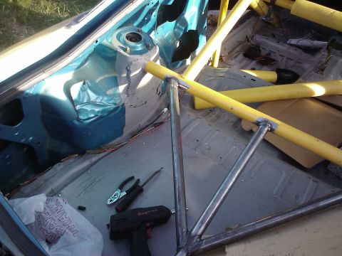 1995 Ford Probe - The interior of a car is shown with a newly installed roll cage, tools, and yellow padding on some bars.