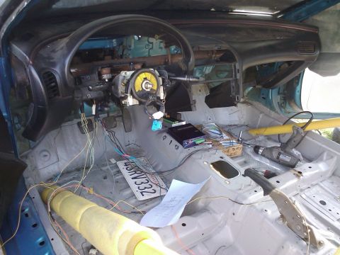 1995 Ford Probe - The interior of a car has been stripped down, with wiring exposed and tools present, suggesting a project in progress.