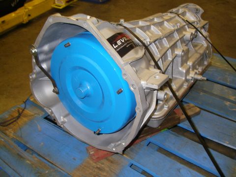 1990 Ford Bronco - Freshly rebuilt automatic transmission finished in silver-gray, strapped to a blue-painted pallet with a bright blue torque converter insta…