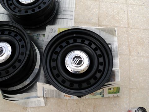 2001 Mercury Grand Marquis - These Mercury hubcaps are sitting on newspaper, possibly waiting to be installed or cleaned.