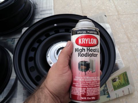 2001 Mercury Grand Marquis - A hand holds a can of Krylon spray paint next to a black steel wheel, suggesting a painting project.