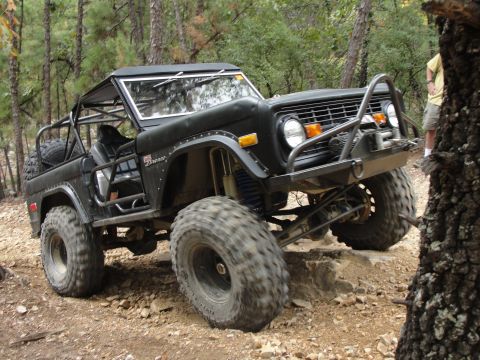 1967 Ford Mustang - This modified Ford Bronco is tackling a rocky trail in a wooded area.