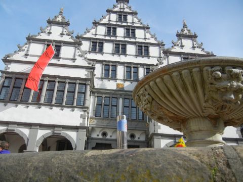 1999 Lincoln Town Car - A stone fountain sits before a grand, multi-gabled building with a red banner hanging from a window.