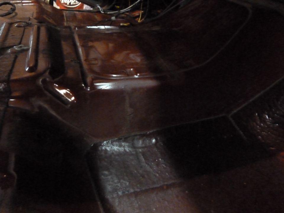 Dark, glossy vehicle floor pan with visible seams and some wiring above