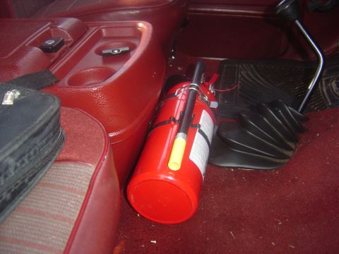 1986 Ford Bronco - Fire extinguisher mounted on the floor of a 1986 Ford Bronco's interior.