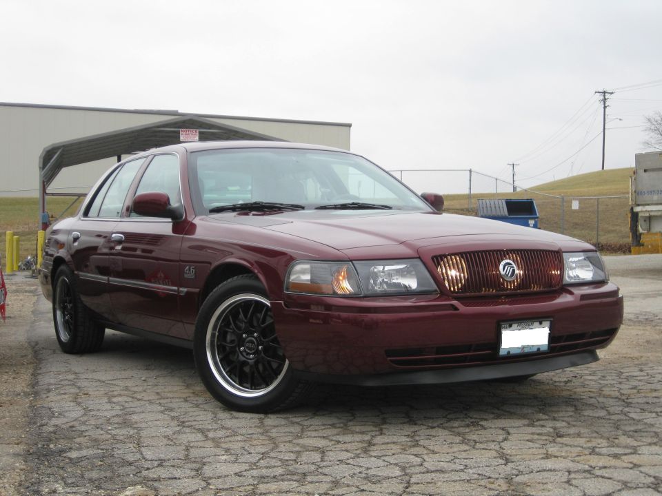 Maroon sedan with black rims parked outside a building. It has a distinctive grille and a '4.6' badge on the fender