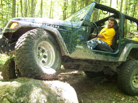 2004 Jeep Wrangler - Driver in yellow shirt navigates a rocky off-road path in a 2004 Jeep Wrangler Rubicon.
