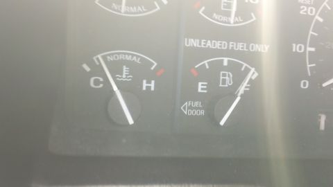 1994 Ford Bronco - Close-up of an instrument cluster showing the coolant temperature gauge reading near cold and the fuel gauge needle at full, with UNLEADED…