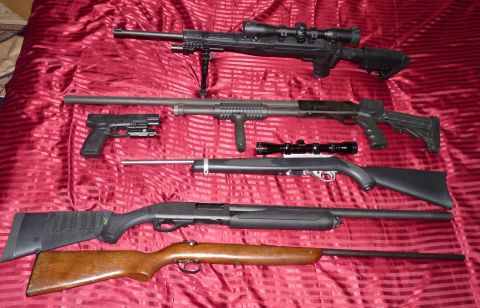 2006 Ford E350 - A variety of firearms, including a scoped rifle, a tactical shotgun, a pistol with a laser sight, and two hunting rifles, are displayed on…