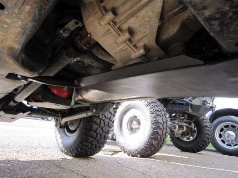 2008 Jeep Wrangler - The undercarriage of a vehicle is shown, highlighting skid plates and tires, with another vehicle partially visible in the background.