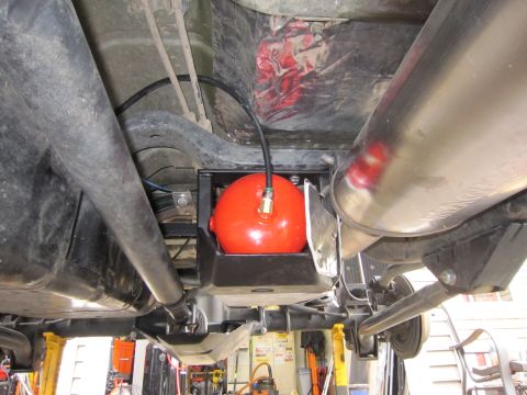 2008 Jeep Wrangler - Underbody view looking up at a lifted vehicle's frame rails, showing a red spherical air tank with a brass fitting and black air line mount…