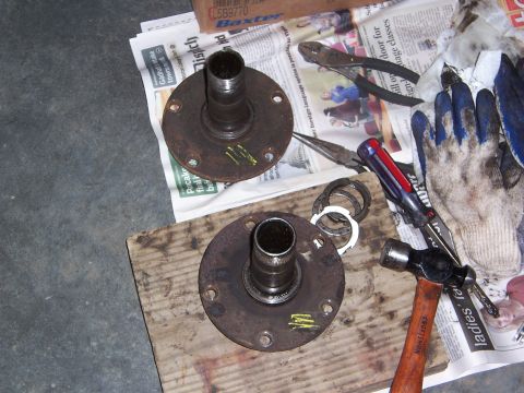 1992 Ford Bronco - Two wheel hubs, a hammer, pliers, screwdriver, and gloves are laid out on newspaper, suggesting a repair or maintenance task.